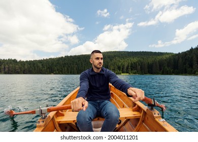 Young Man Paddling Canoe On A Forest Lake