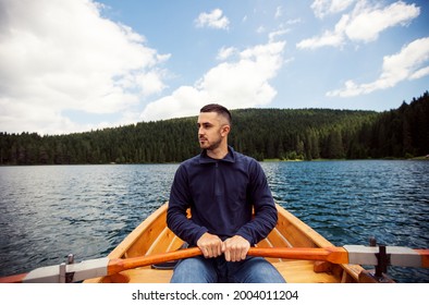 Young Man Paddling Canoe On A Forest Lake