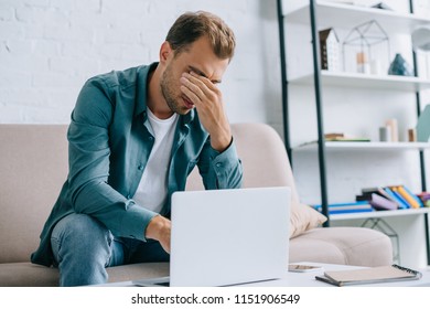 young man with pain in eyes using laptop at home - Shutterstock ID 1151906549