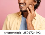 Young man in pain from a toothache, touching his jaw with a pained expression, highlighting oral health importance and the need for timely dentist visits. Dental care concept