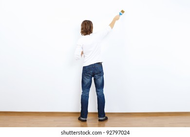 Young Man With Paint Brush And Blank White Wall