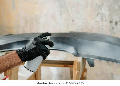 Young man painting a car bumper with spray can. Overhaul cars plastic bumper cover at auto repair shop. Worker using protective gear while working to keep from inhaling harmful fumes. Selective focus. - Powered by Shutterstock