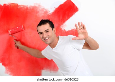 Young Man Painting House Wall In Red
