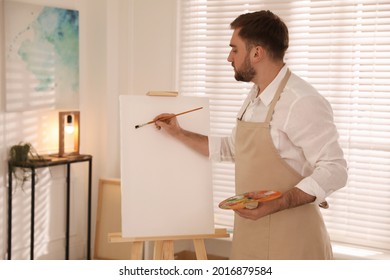 Young Man Painting On Easel With Brush In Artist Studio