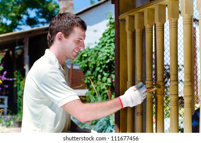 Young Man Painting Wooden Fence In The Garden