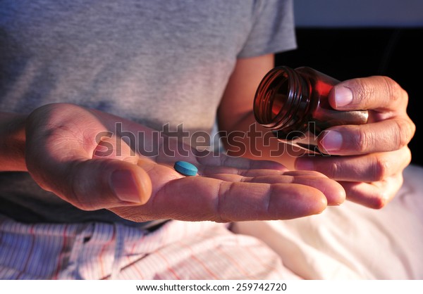a\
young man in pajamas in bed about to take a blue\
pill