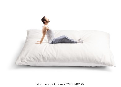 Young Man In Pajamas Stretching On A Big Pillow Isolated On White Background