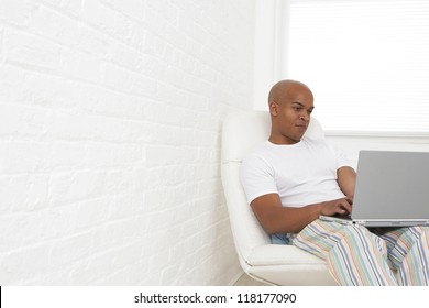 Young Man In Pajamas Working On A Laptop Computer For A Short While Before He Goes To Bed