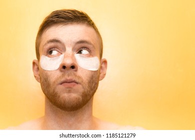 Young man with patches under the eyes on a yellow background. Concept of cosmetology for men. - Powered by Shutterstock