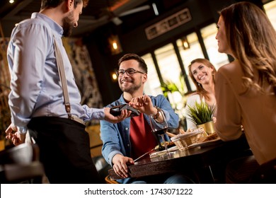 Young Man Paying With Contactless Credit Card In The Restaurant After Dinner