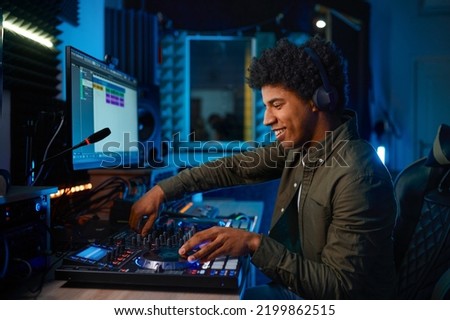 Young man paying music on sound mixer in radio station