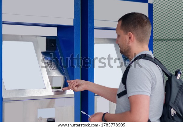 A young man pays for the purchase of a\
high-speed train ticket at the self-service ticket office in the\
station building. The concept of online\
travel