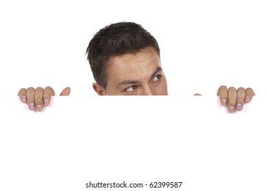 young man peeking behind empty white billboard