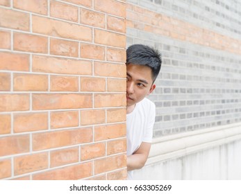 Young man peeking behind wall.