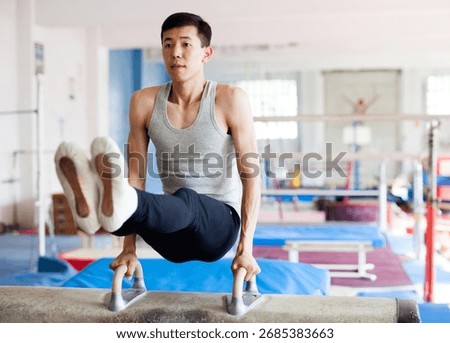 Young man performing gymnastic elements on pommel