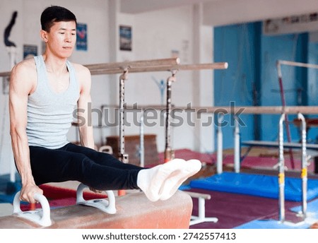 Young man performing gymnastic elements on pommel