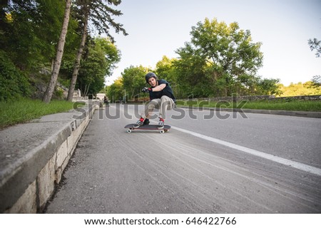 A young man performs a complicated stunt on a longboard