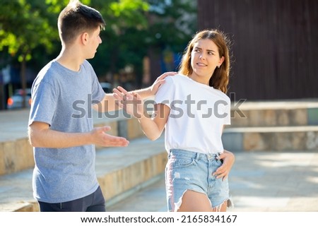 Young man is pestering teenage girl on the street