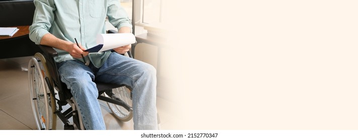 Young Man With Physical Disability Working With Documents In Office. Banner For Design With Space For Text