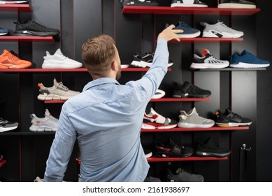 young man picking a sporty shoes in the shop, new sneakers in sports store for men, mens shopping sports shoes - Shutterstock ID 2161938697