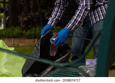 Young Man Picking Up Trash Bottles Plastic In The Park To Clean The Environment