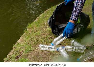 Young Man Picking Up Trash Bottles Plastic In The Park To Clean The Environment