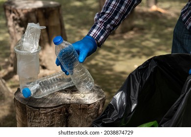 Young Man Picking Up Trash Bottles Plastic In The Park To Clean The Environment