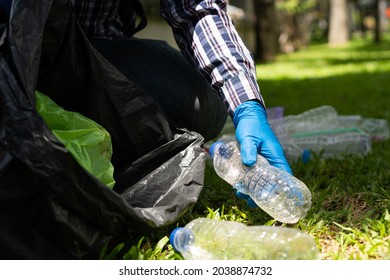 Young Man Picking Up Trash Bottles Plastic In The Park To Clean The Environment