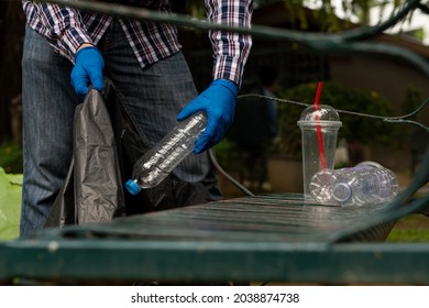 Young Man Picking Up Trash Bottles Plastic In The Park To Clean The Environment