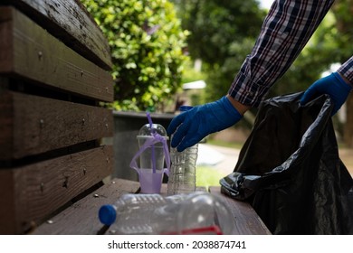 Young Man Picking Up Trash Bottles Plastic In The Park To Clean The Environment