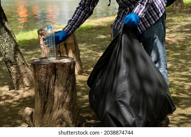 Young Man Picking Up Trash Bottles Plastic In The Park To Clean The Environment