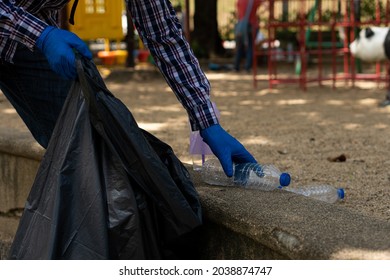 Young Man Picking Up Trash Bottles Plastic In The Park To Clean The Environment