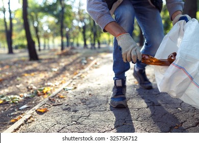young man picking up trash outdoor. close up