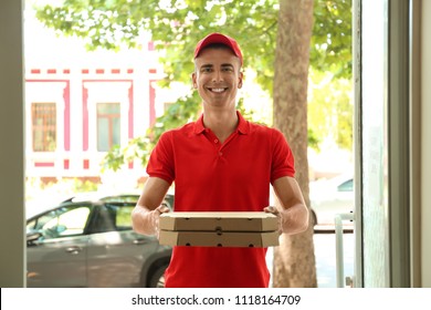 Young man with pizza boxes at doorway. Food delivery service