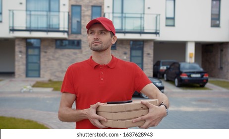 Young man pizza courier holding food carton boxes searching customer's house walking in modern street in the city center. Food delivery. - Powered by Shutterstock