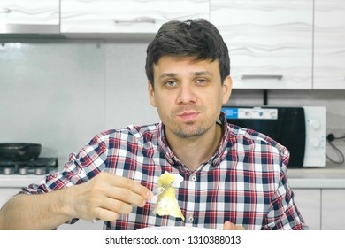 Young Man In A Plaid Shirt Eating Scrambled Eggs Sitting At The Table.