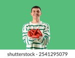 Young man with plate of tasty sausages on green background