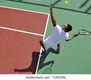 young man play tennis outdoor on orange tennis court at early morning - Powered by Shutterstock