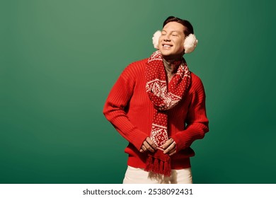 The young man playfully poses in a vibrant red sweater with a warm scarf and fluffy earmuffs. - Powered by Shutterstock