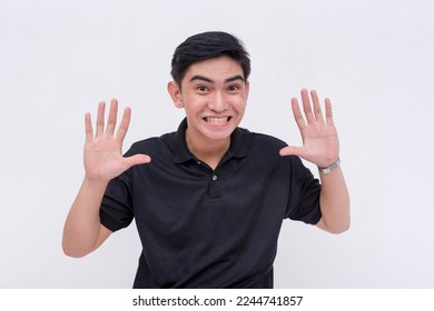 A young man playfully surrenders while smiling. Giving up during a lighthearted moment. Isolated on a white backdrop. - Shutterstock ID 2244741857