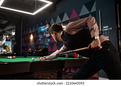 Young man playing billiard at night club