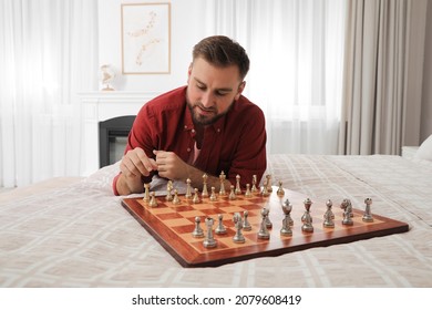 Young Man Playing Chess Alone On Bed At Home