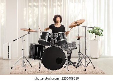 Young man playing drums at home inside a living room - Powered by Shutterstock