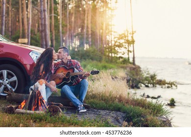 young man playing guitar for his girlfriend on a road trip - Powered by Shutterstock