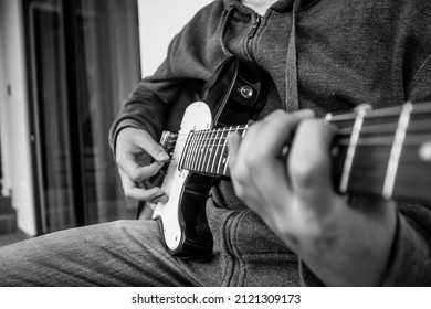 Young Man Playing Guitar And Learning From His Phone