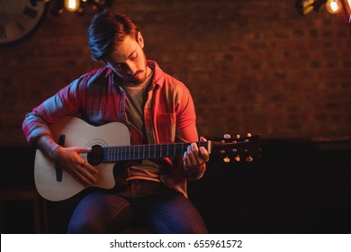 Young man playing guitar in pub - Powered by Shutterstock
