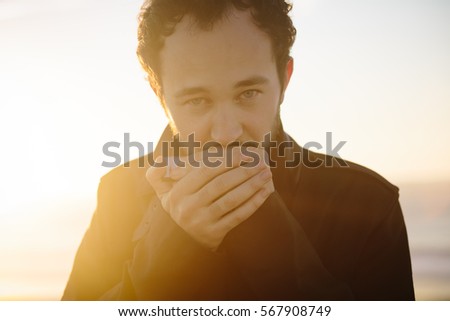 Young man playing the harmonica, against the sun. With shallow depth of field. 