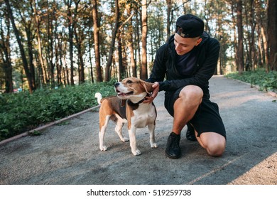 Young man playing with his dog in forest. Evening walk with pet on nature. Healthy lifestyle, domestic animal, nature concept