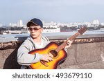 Young man playing on guitar on the roof of a tall building