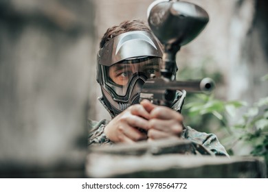 Young man playing paintball battle game with his friends, wearing a camouflage and protective mask, banner, leisure activity